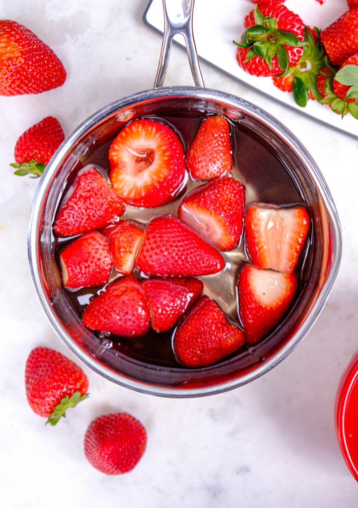 Strawberries simmering in simple syrup in a small saucepan. 