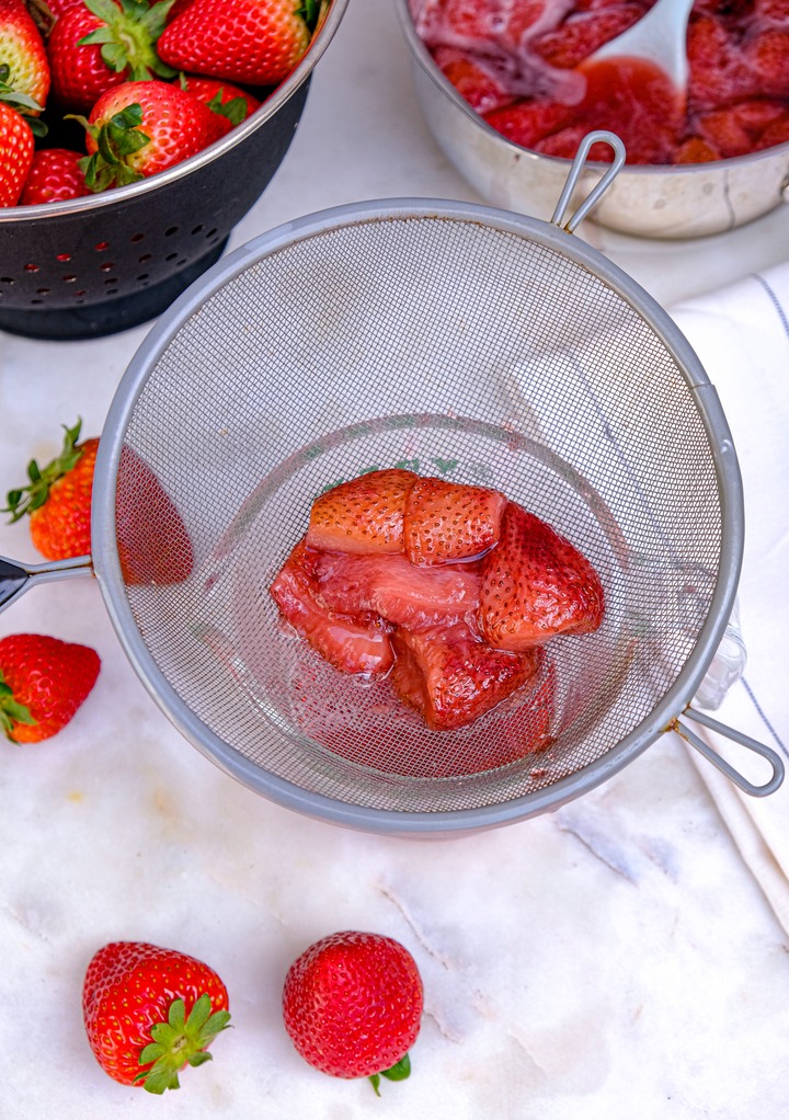 Straining strawberries that have been cooked. 