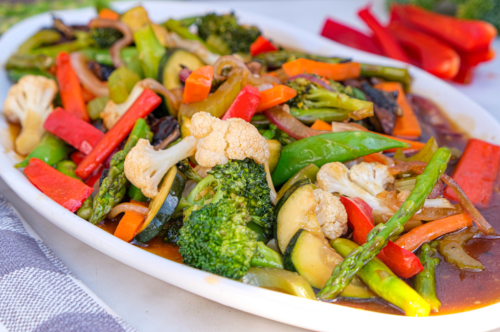 Vegetables on a serving dish with a sir fry sauce. 