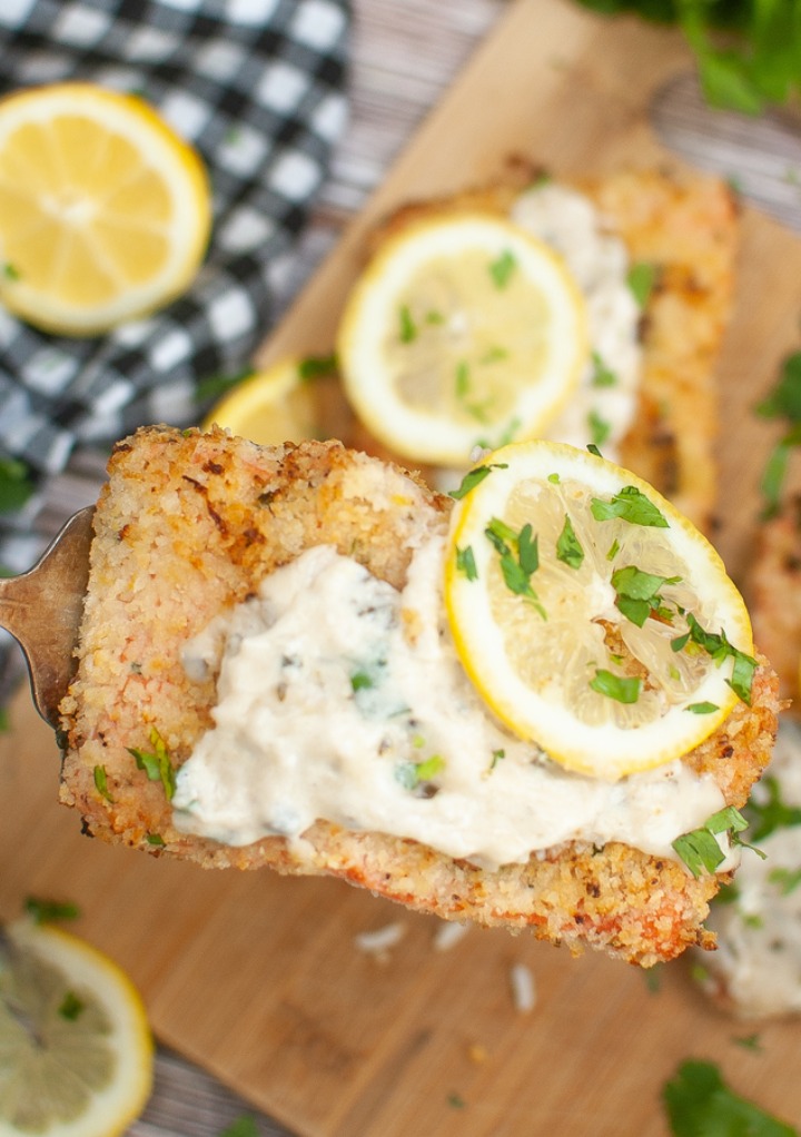 Cooked salmon topped with a wine sauce and lemon slices. 