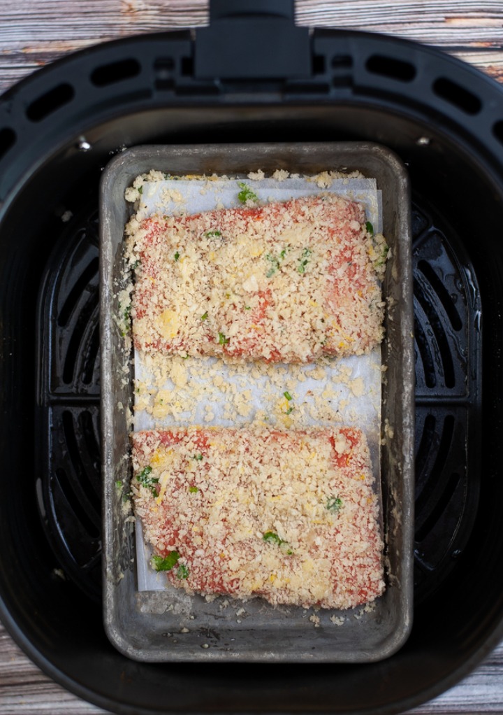 Two pieces of salmon in a small baking dish in an air fryer insert.