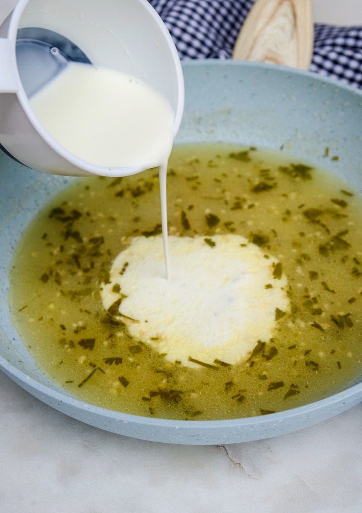 Adding heavy cream to white wine sauce. 