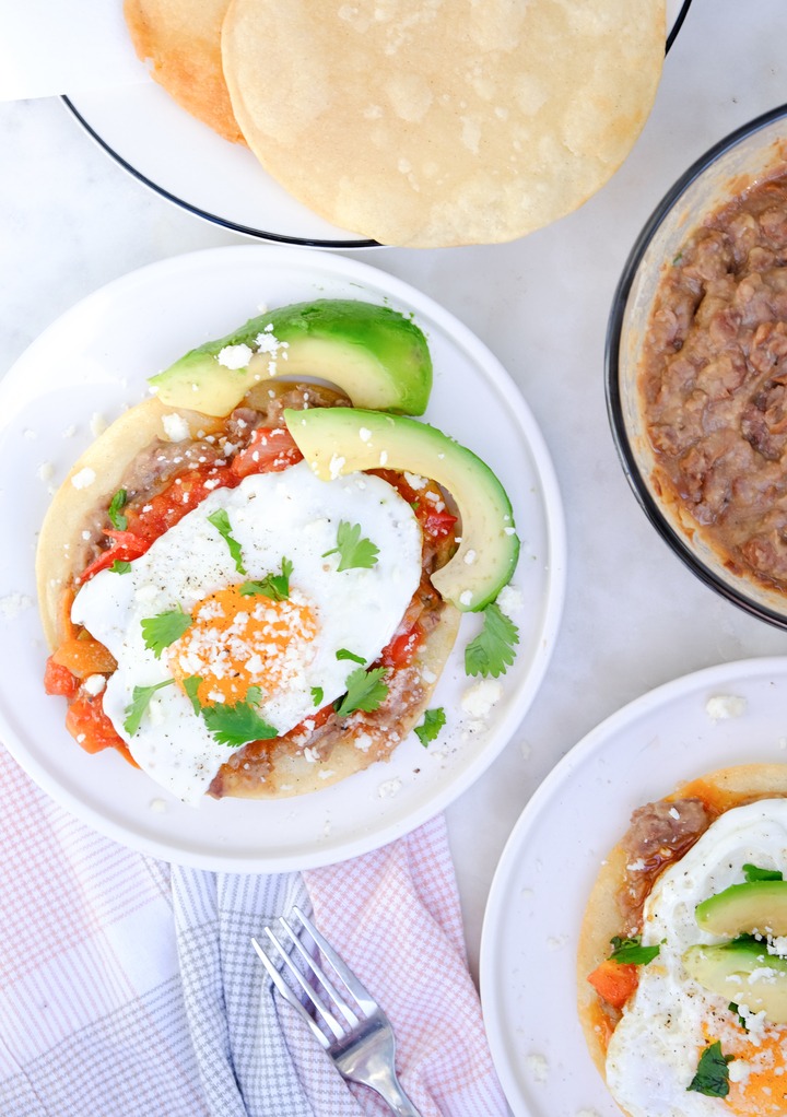 Top view of huevos rancheros with beans and tortillas on the side. 