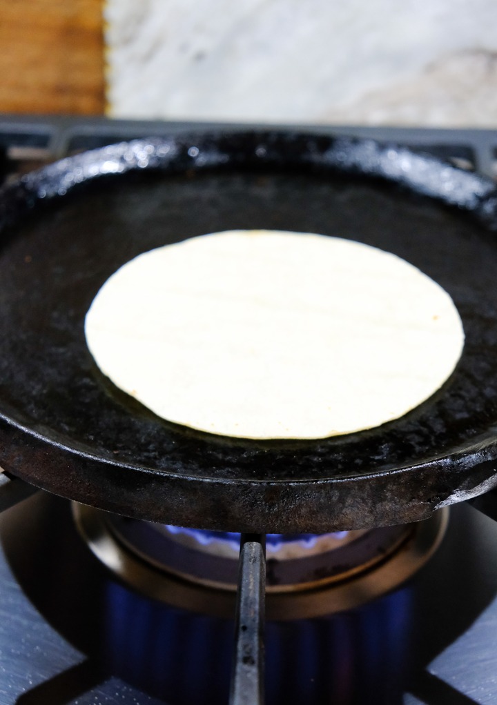 Corn tortilla on a cast iron skillet warming. 