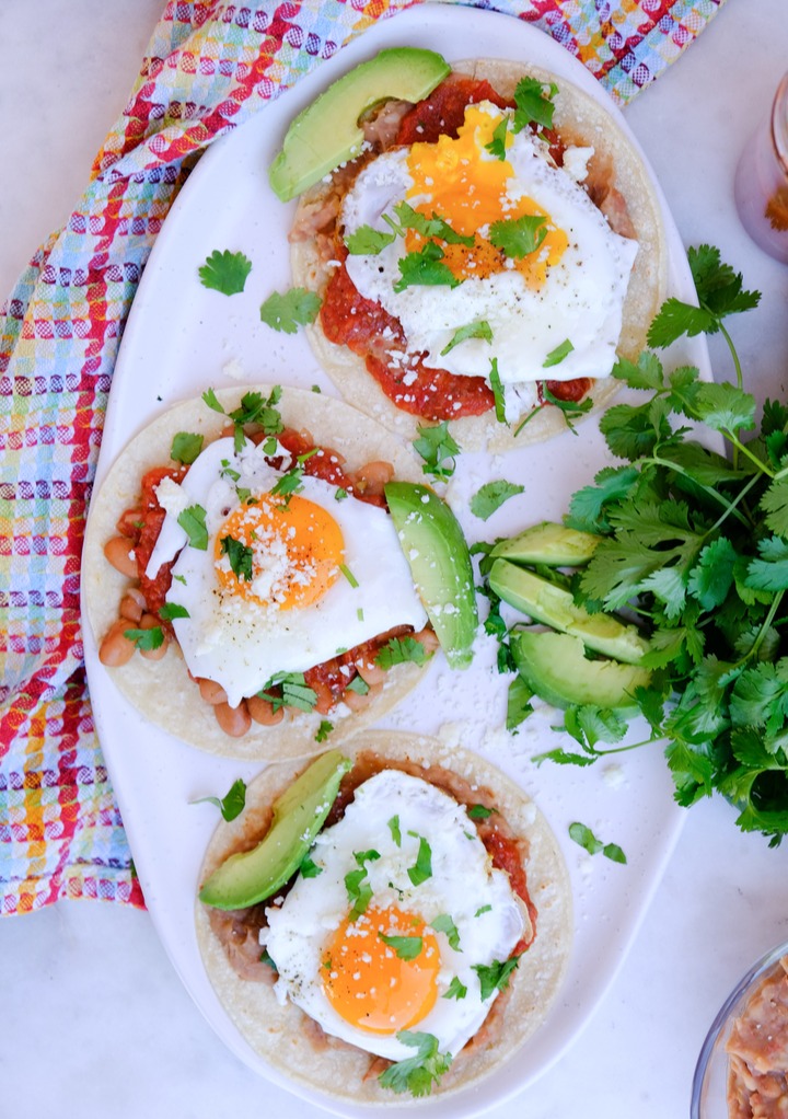 A white serving dish of huevos rancheros topped with cilantro.