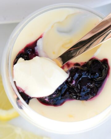Top view of lemon posset in a clear dish with a scoop taken out with a spoon.