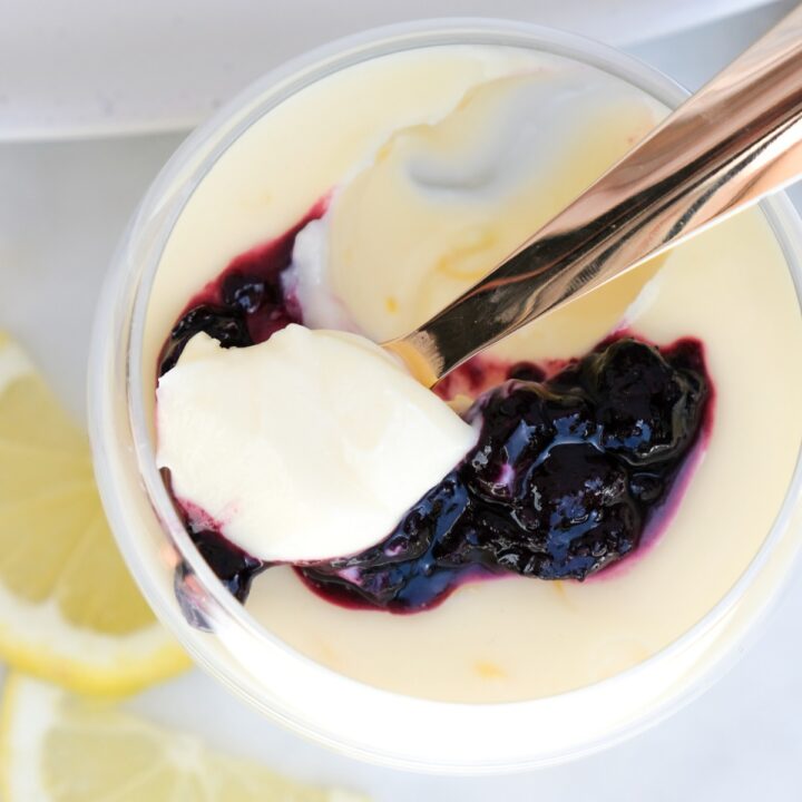Top view of lemon posset in a clear dish with a scoop taken out with a spoon.