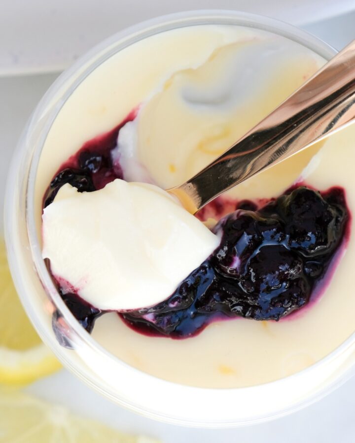 Top view of lemon posset in a clear dish with a scoop taken out with a spoon.