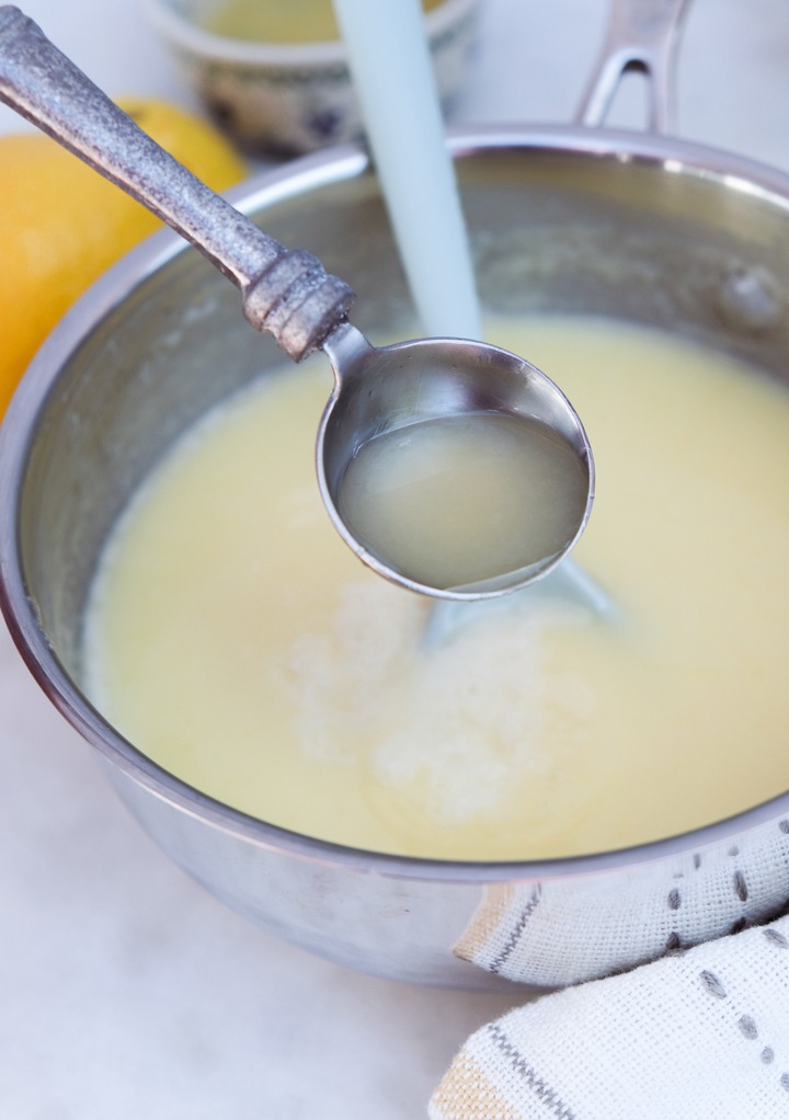 Fresh lemon juice added to a saucepan with lemon posset. 