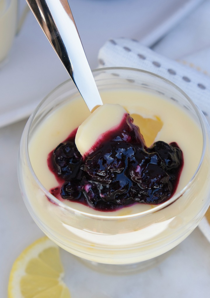 Lemon posset topped with blueberry sauce ready to eat. 