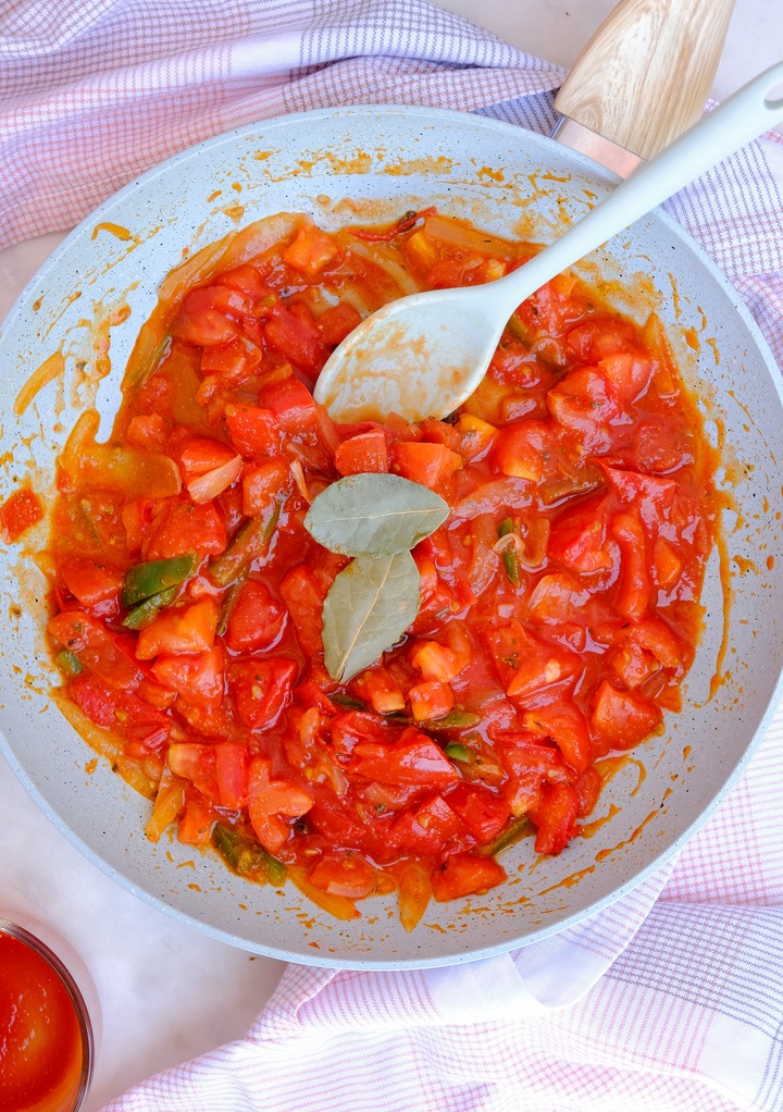 Sauted tomatoes, onions, jalapeno with bay leaves in a skillet.