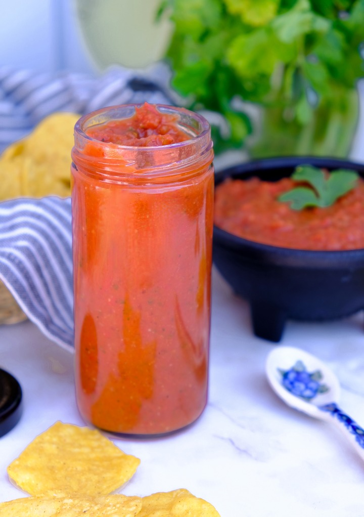 Ranchero sauce in a glass jar with salsa in the background. 