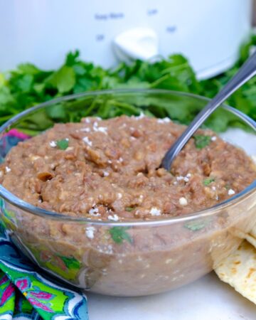 Homemade refried beans in a clear glass bowl.