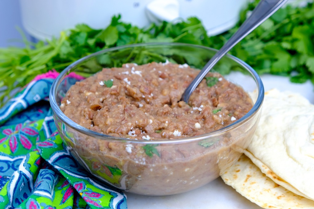 Cooked refried beans with tortillas on the side ready to eat. 