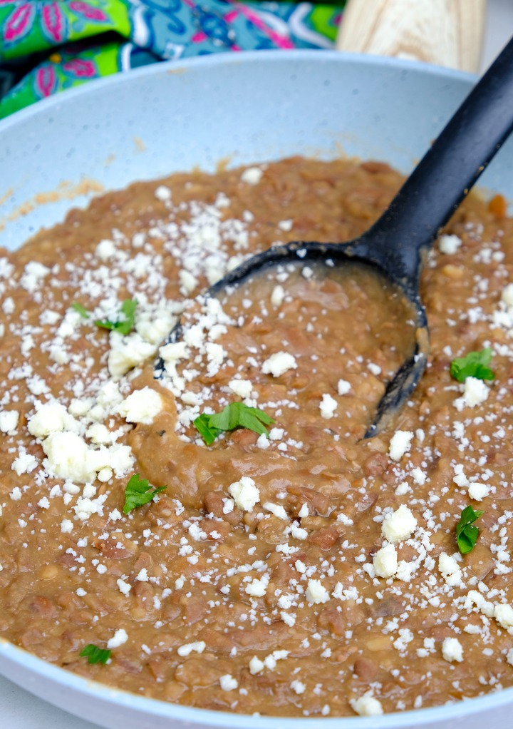 Homemade refried beans topped with cheese and cilantro in a skillet. 