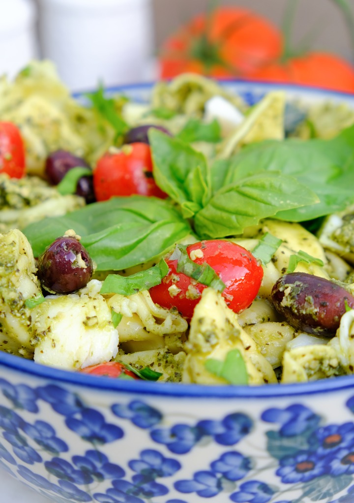 Tortellini pasta salad with pesto sauce in a blue flowered bowl. 