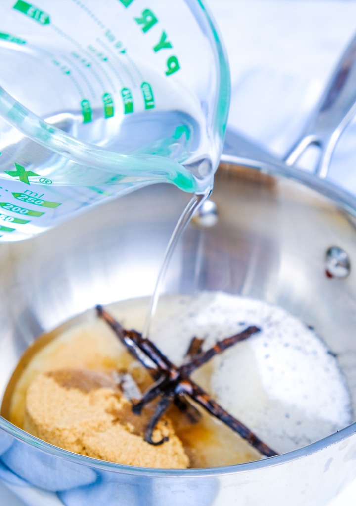 Adding water to a small saucepan with sugar and vanilla beans. 