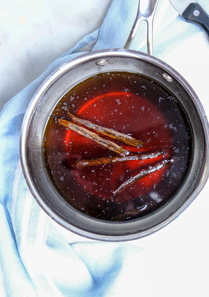 Vanilla syrup simmering in a small saucepan with a vanilla pod. 