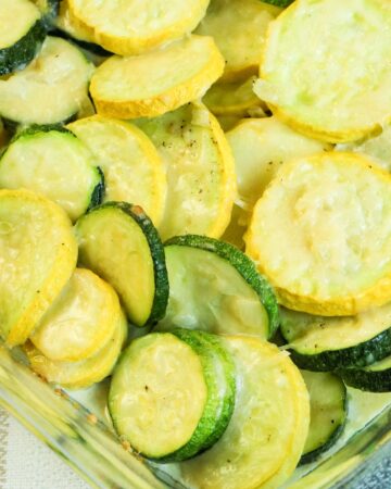 Zucchini and squash roasted in a clear baking dish.