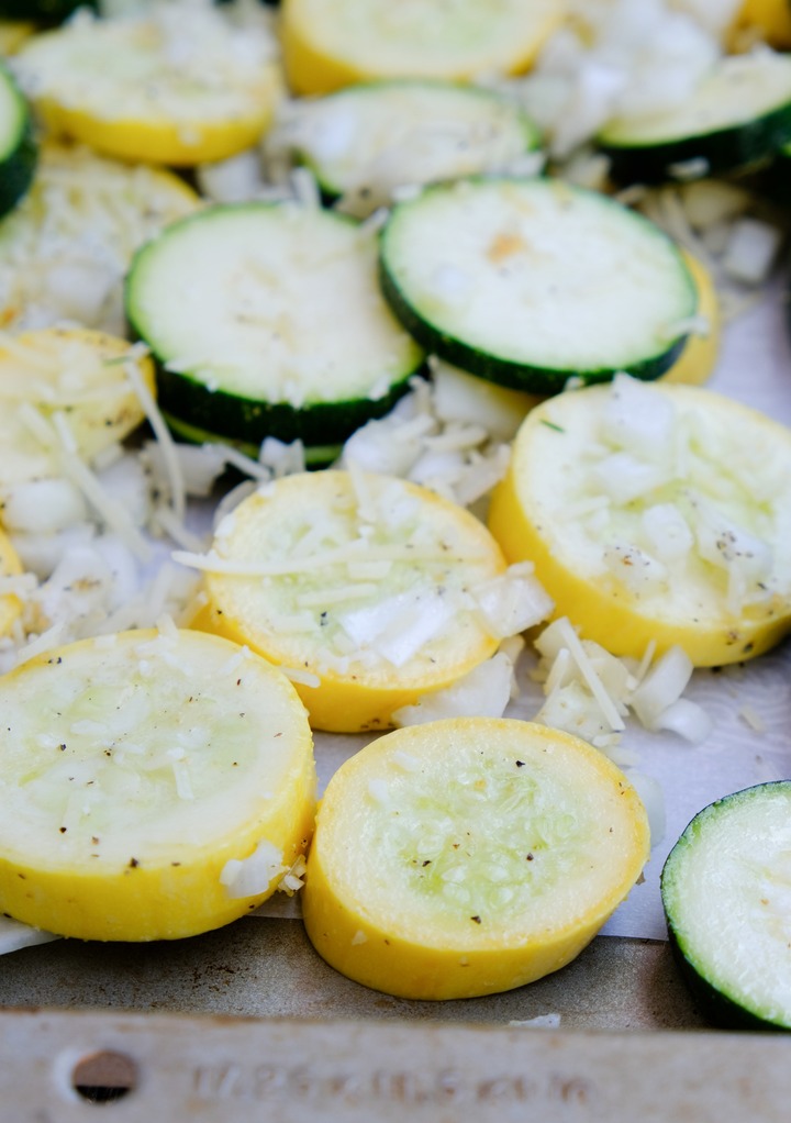 Seasoned zucchini slices on a baking sheet. 