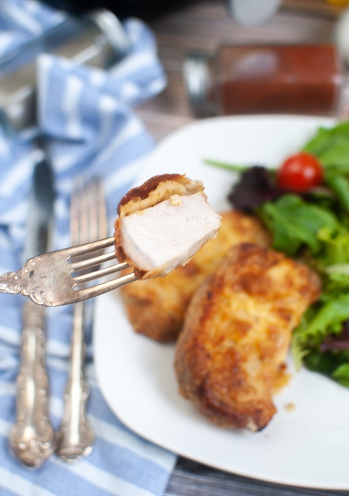 A slice of pork chop picked up with a fork. 