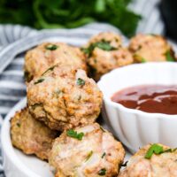 Turkey meatballs cooked in an air fryer on a white serving plate with a side of bbq sauce.