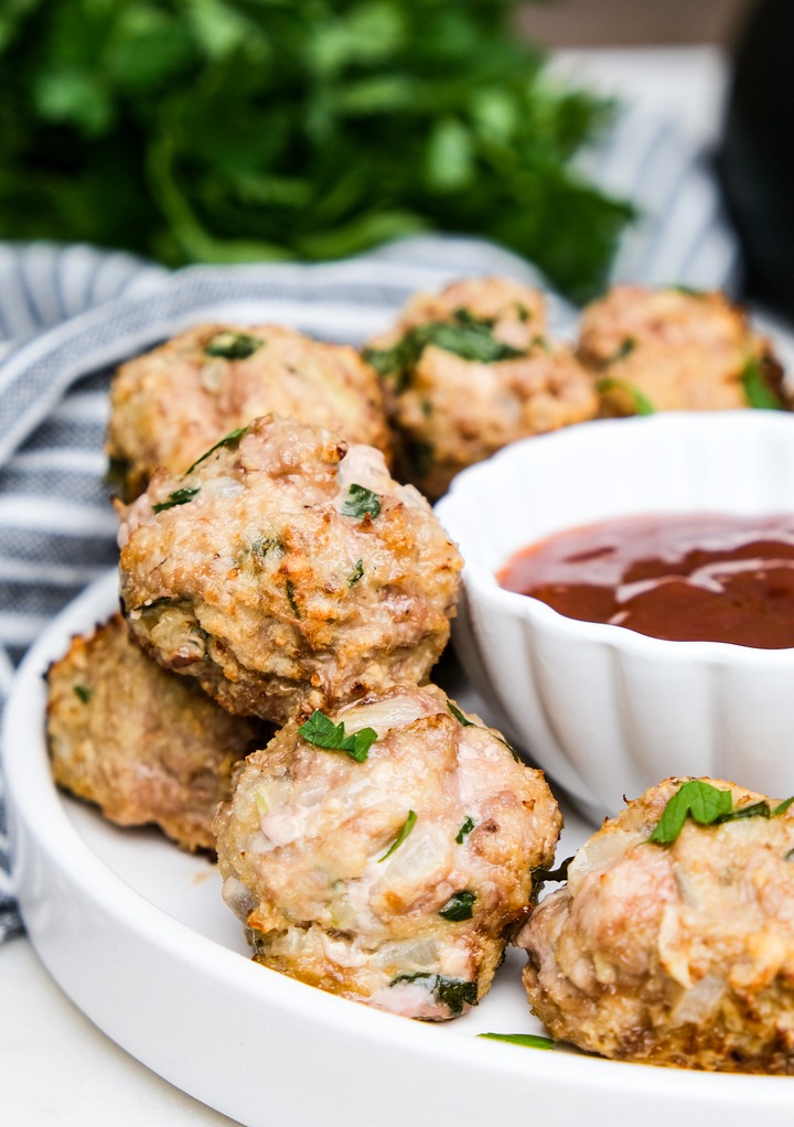 Turkey meatballs on a white plate with a side of dipping sauce. 