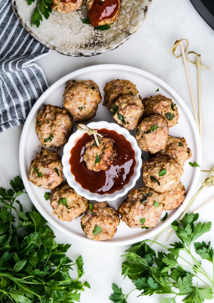 Top view of turkey meatballs on a white plate with a dipping sauce in the middle of the plate. 