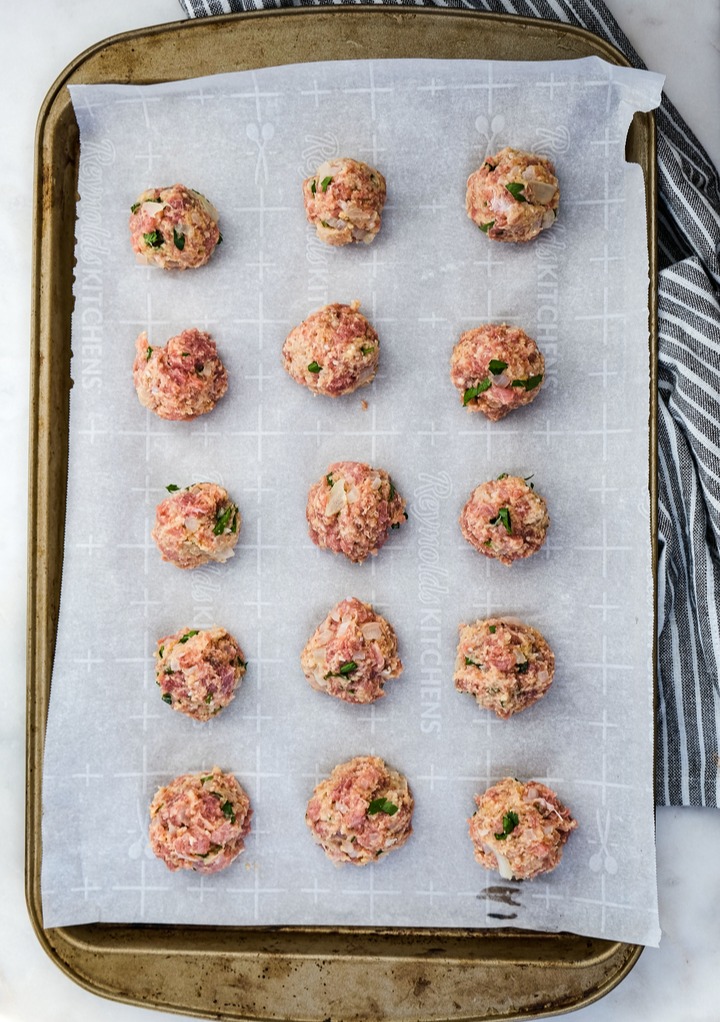 Turkey meatballs on a baking sheet lined with parchment paper before air frying. 