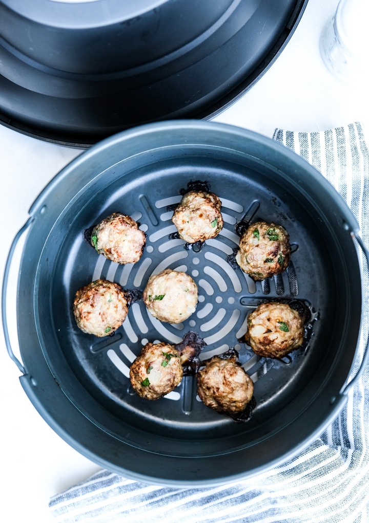 Cooked turkey meatballs in the basket of the air fryer. 