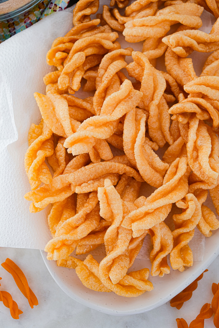 Fried Chicharrones de harina on a plate lined with paper towels. 