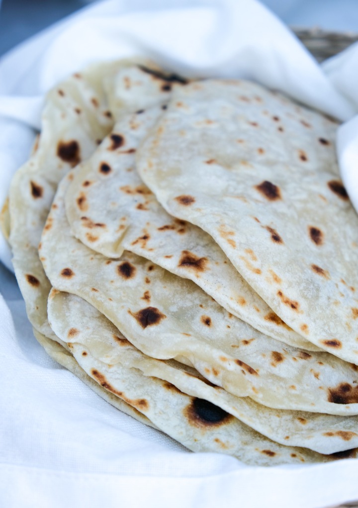 Homemade flour tortilla recipe without lard stacked wrapped in a white kitchen towel.
