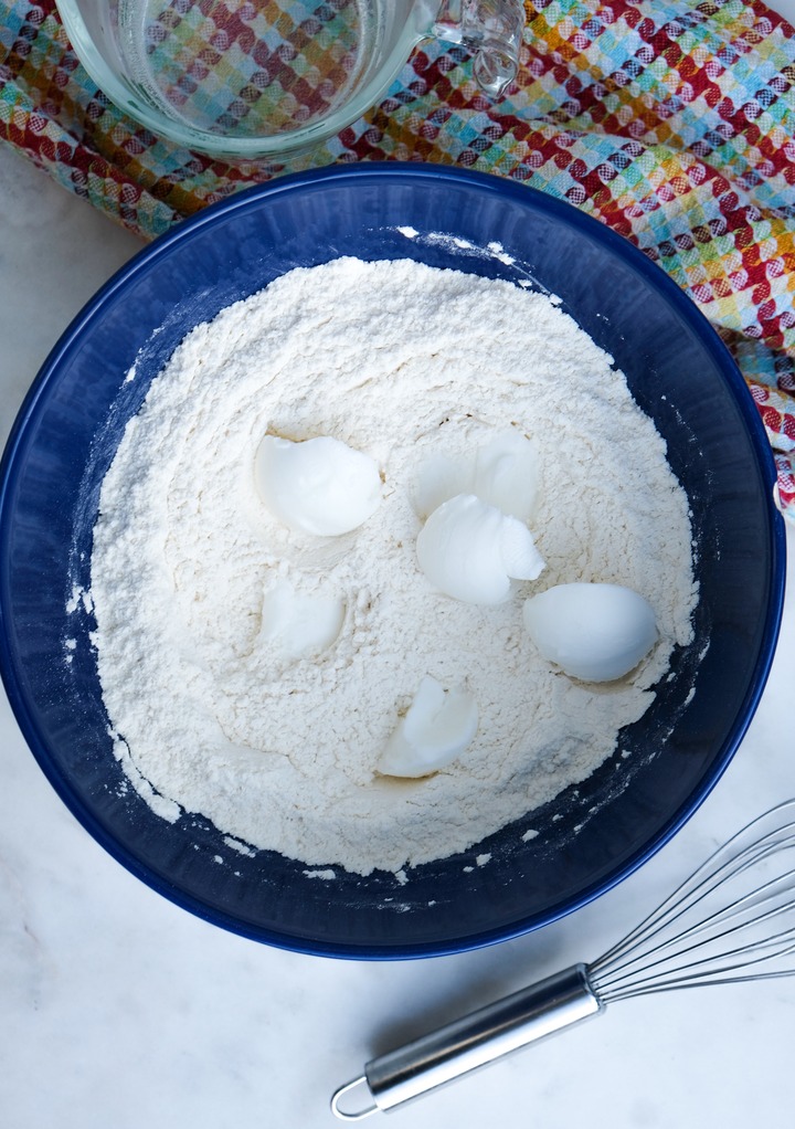 Flour with shortening to make tortillas in a blue mixing bowl. 