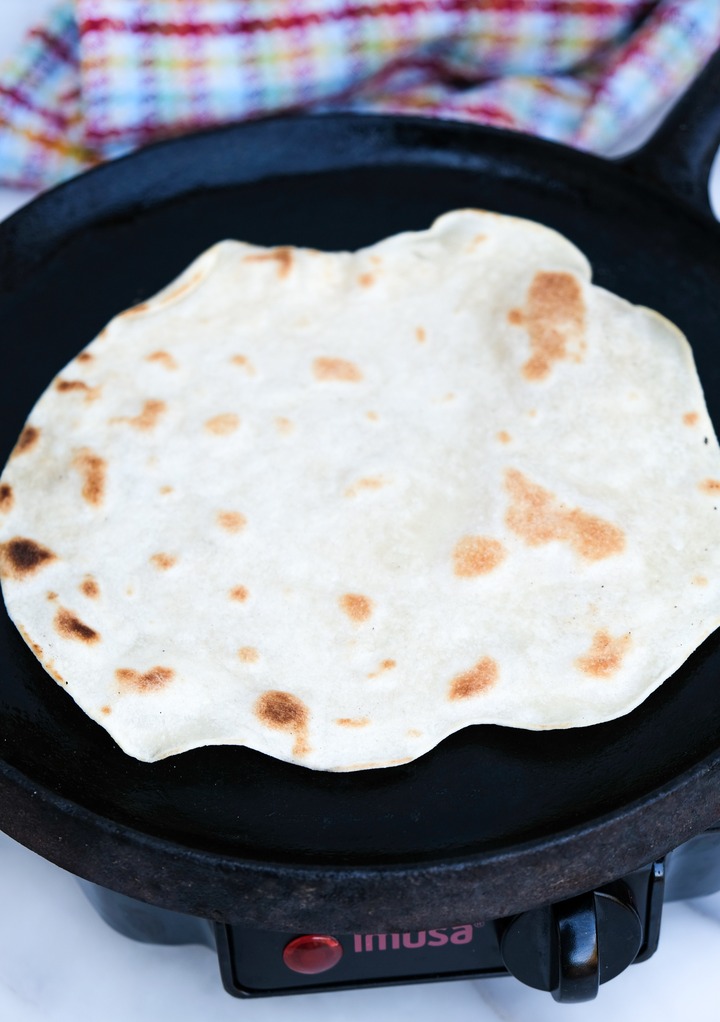 Tortilla on an round comal cooking it. 