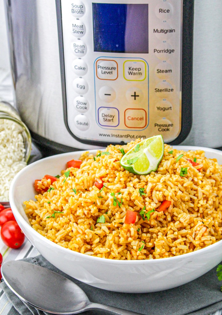 Mexican rice in a white serving bowl with a slice of lime ready to serve. 