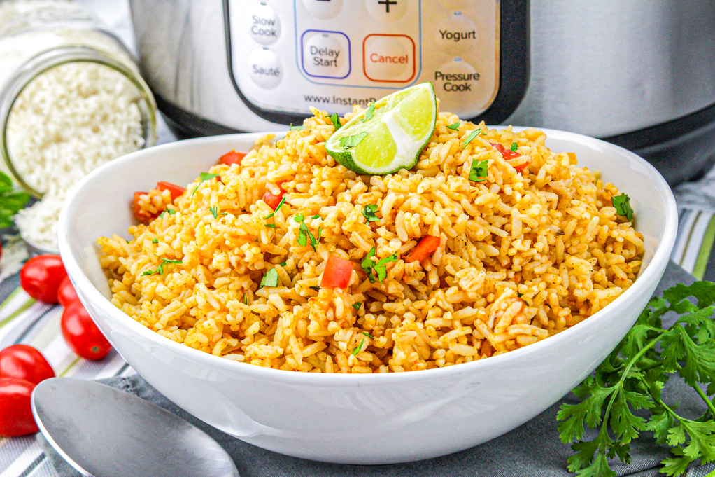 Homemade Mexican rice topped with a lime slice and diced cilantro in a white bowl. 