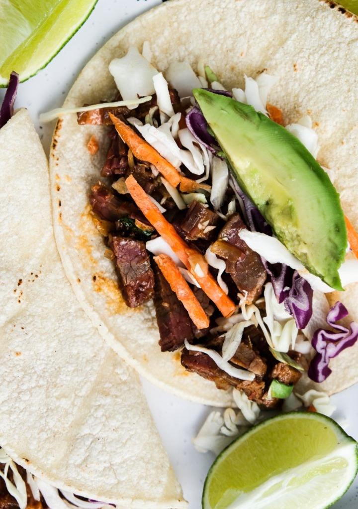 Top view of open faced tacos made with leftover brisket and a slice of avocado on a corn tortilla.