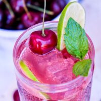 Homemade cherry mojito with lime and fresh cherry juice in a tall cocktail glass.