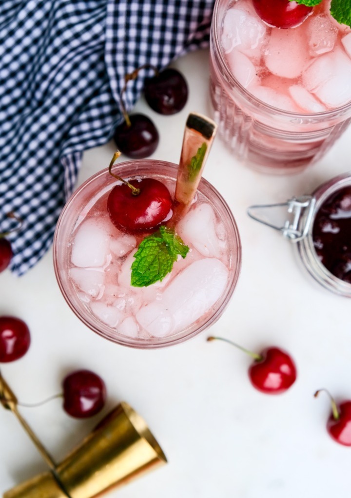 Overhead view of two cherry mojito cocktails with fresh cherries and mint. 