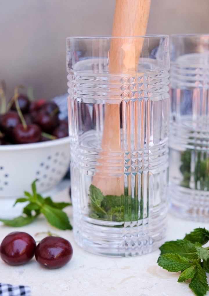 Fresh mint in a tall clear glass with a muddle.