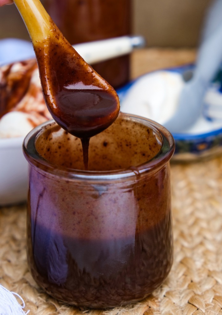 Chocolate sauce with a small spoon dipped into the jar ready to use. 