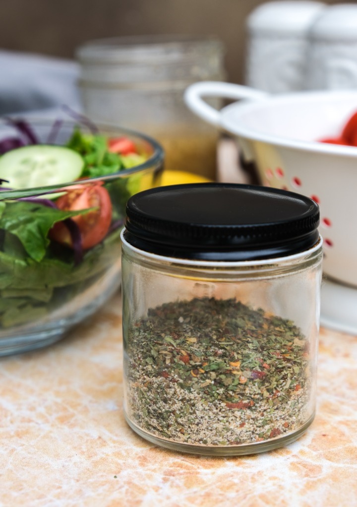 A mix of dry herbs in a clear jar with a lid. 
