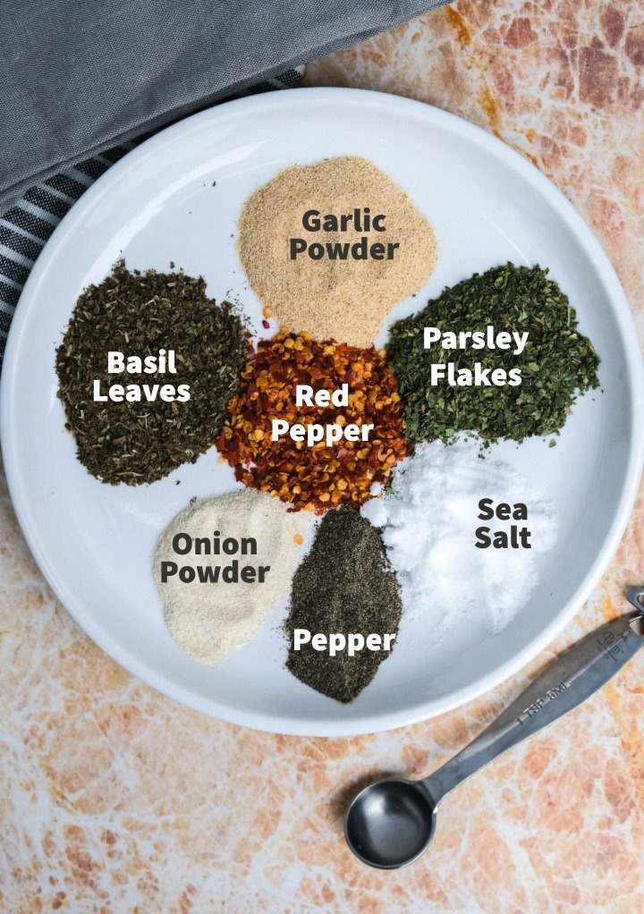 Dry spices on a white plate needed to make an Italian dressing mix. 