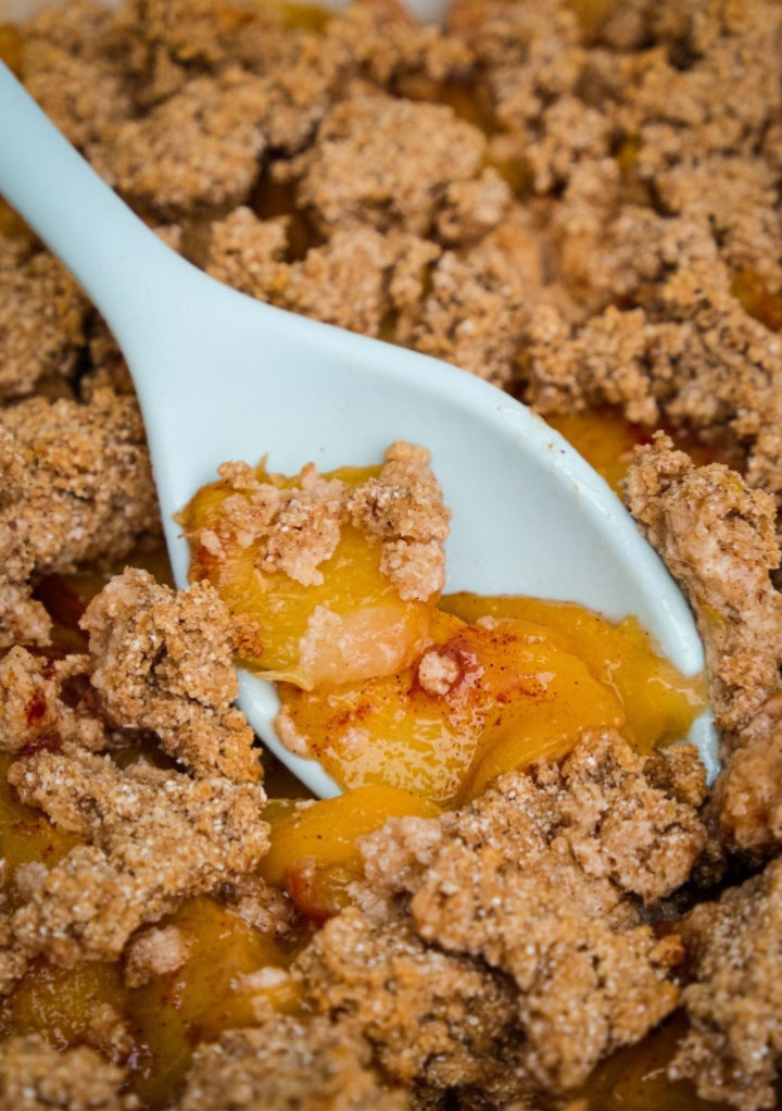 Low carb peach crumble with a spoon scooping out the dessert. 
