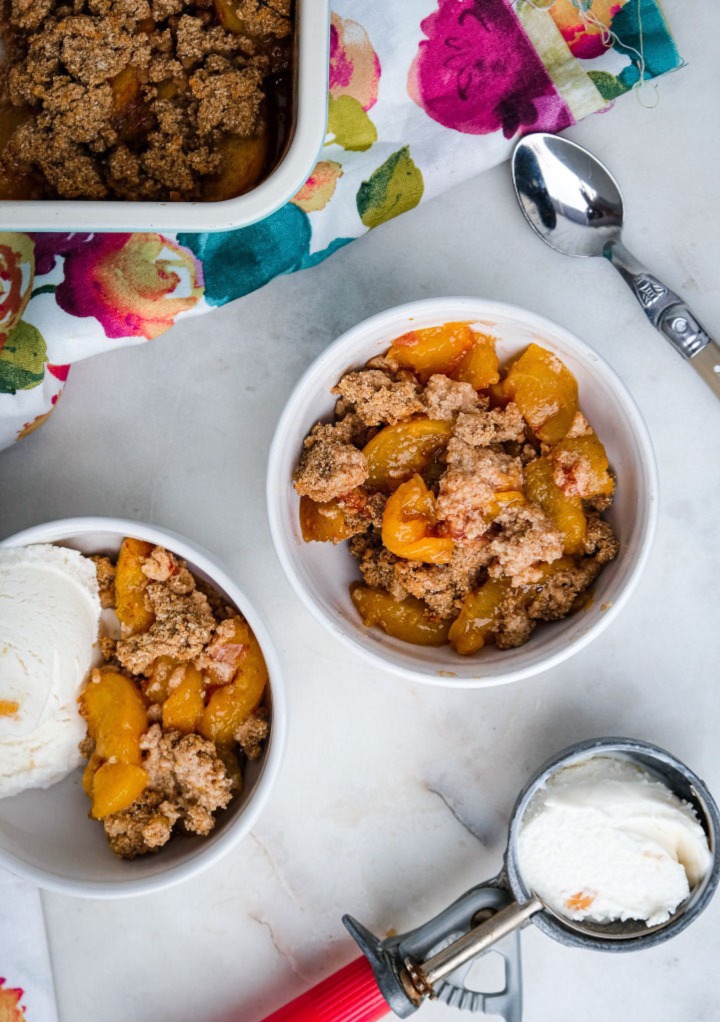 Overhead view of peach crumble with vanilla ice cream. 