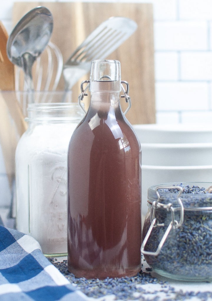 A tall glass jar with homemade lavender simple syrup. 