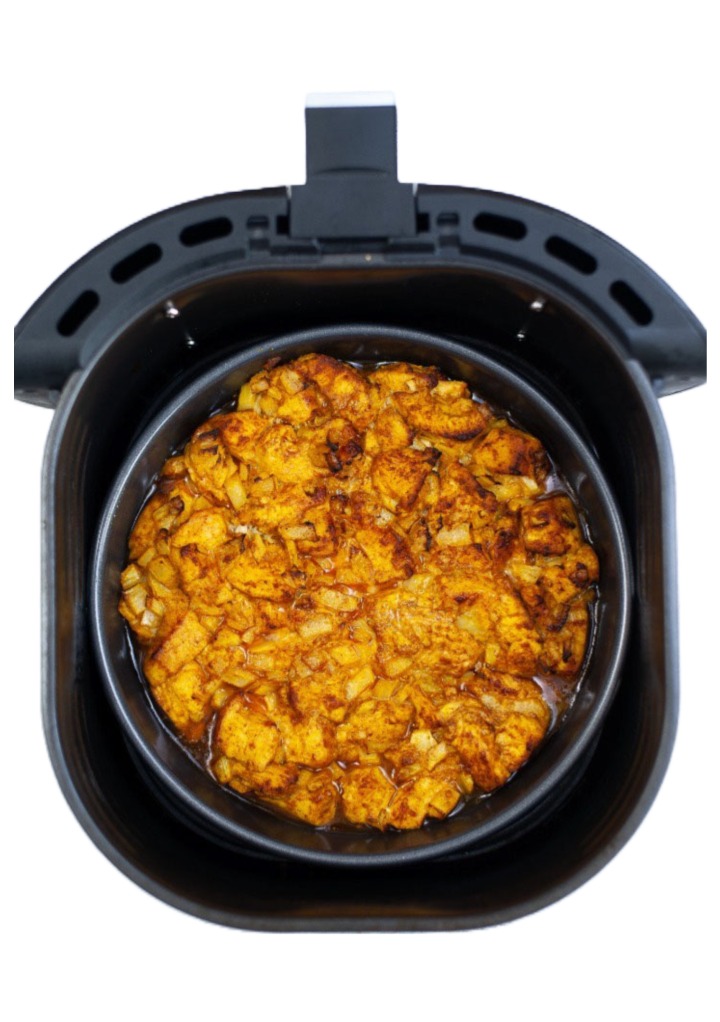 Chicken curry in the center of an air fryer basket. 