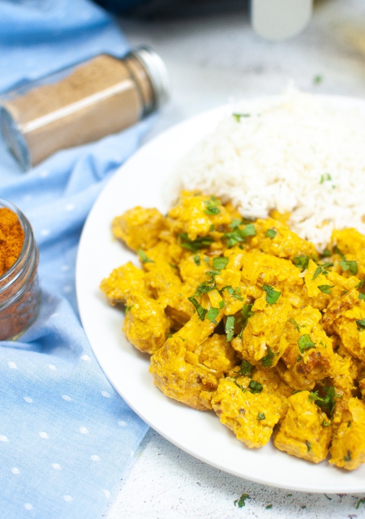 Air fryer curry chicken on a white serving plate with rice on the side. 