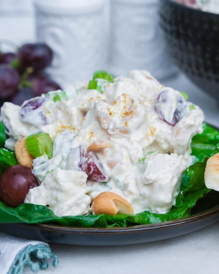 Curried chicken salad recipe with cashews and grapes on a bed of lettuce.