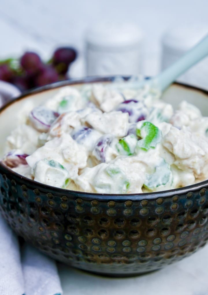 Chicken salad in a brown bowl with salt and pepper shakers on the side. 